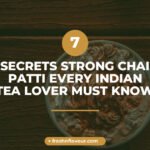 Strong chai patti brewing in glass cup with whole spices and CTC black tea leaves visible, warm gold